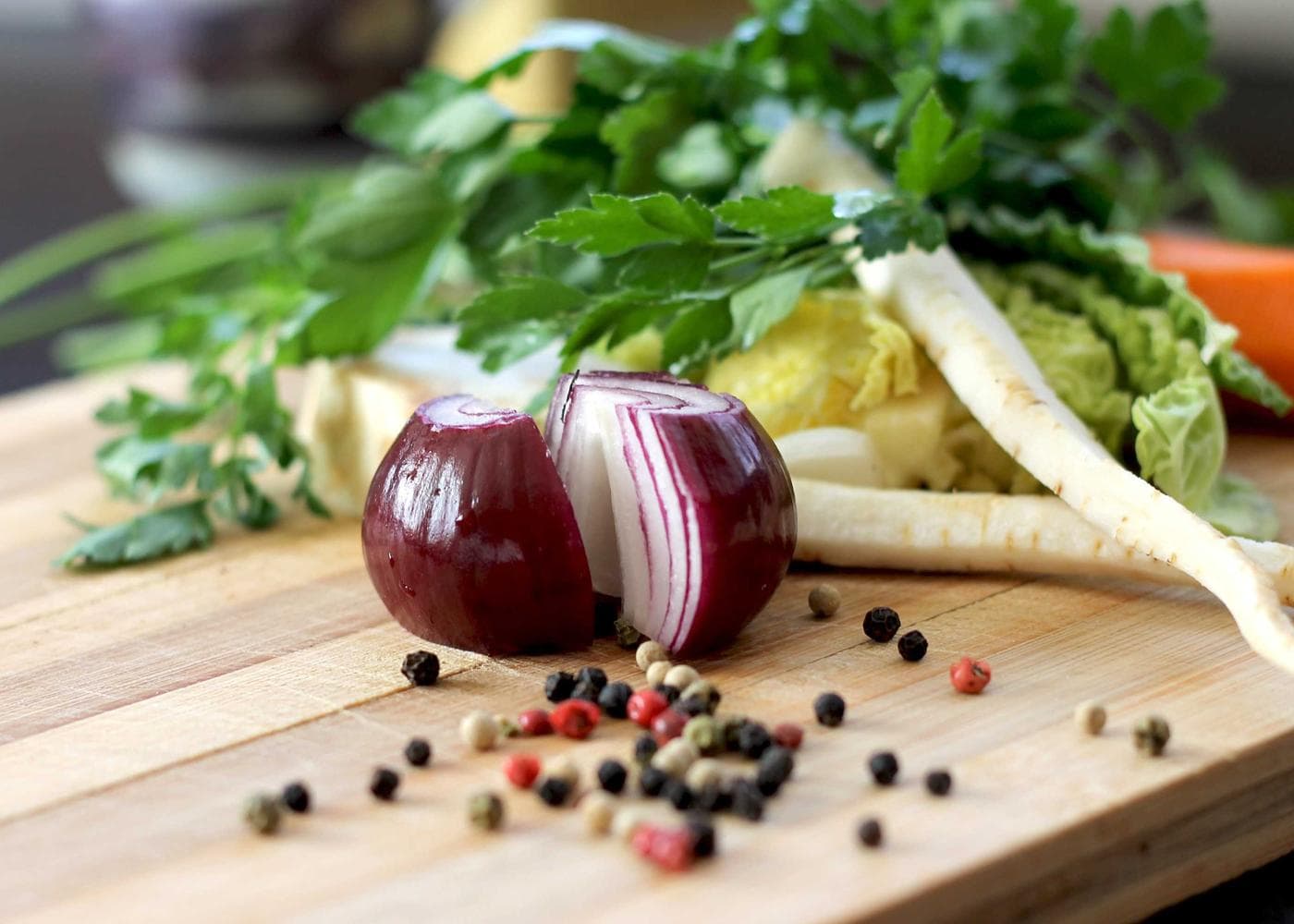Fresh vegetables, herbs and peppercorns on a wooden board