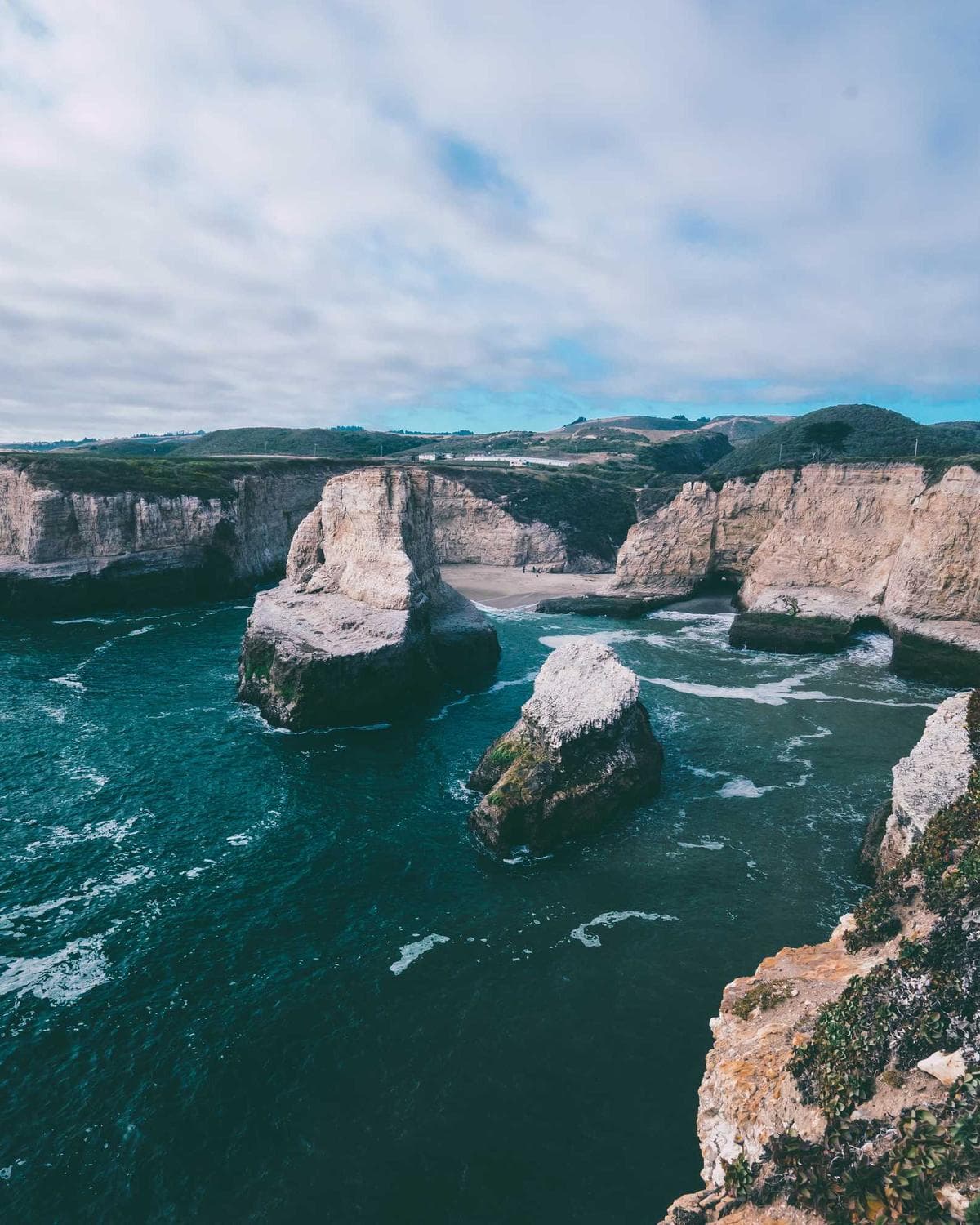 Sea cliffs and rock stacks along a green coastline